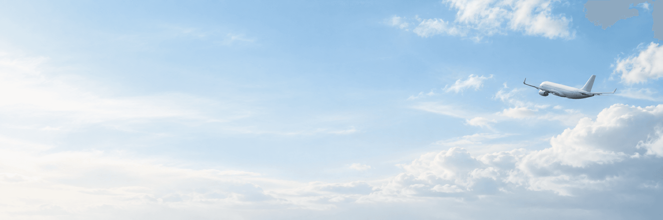 Passenger aircraft flying through a soft blue sky above white clouds